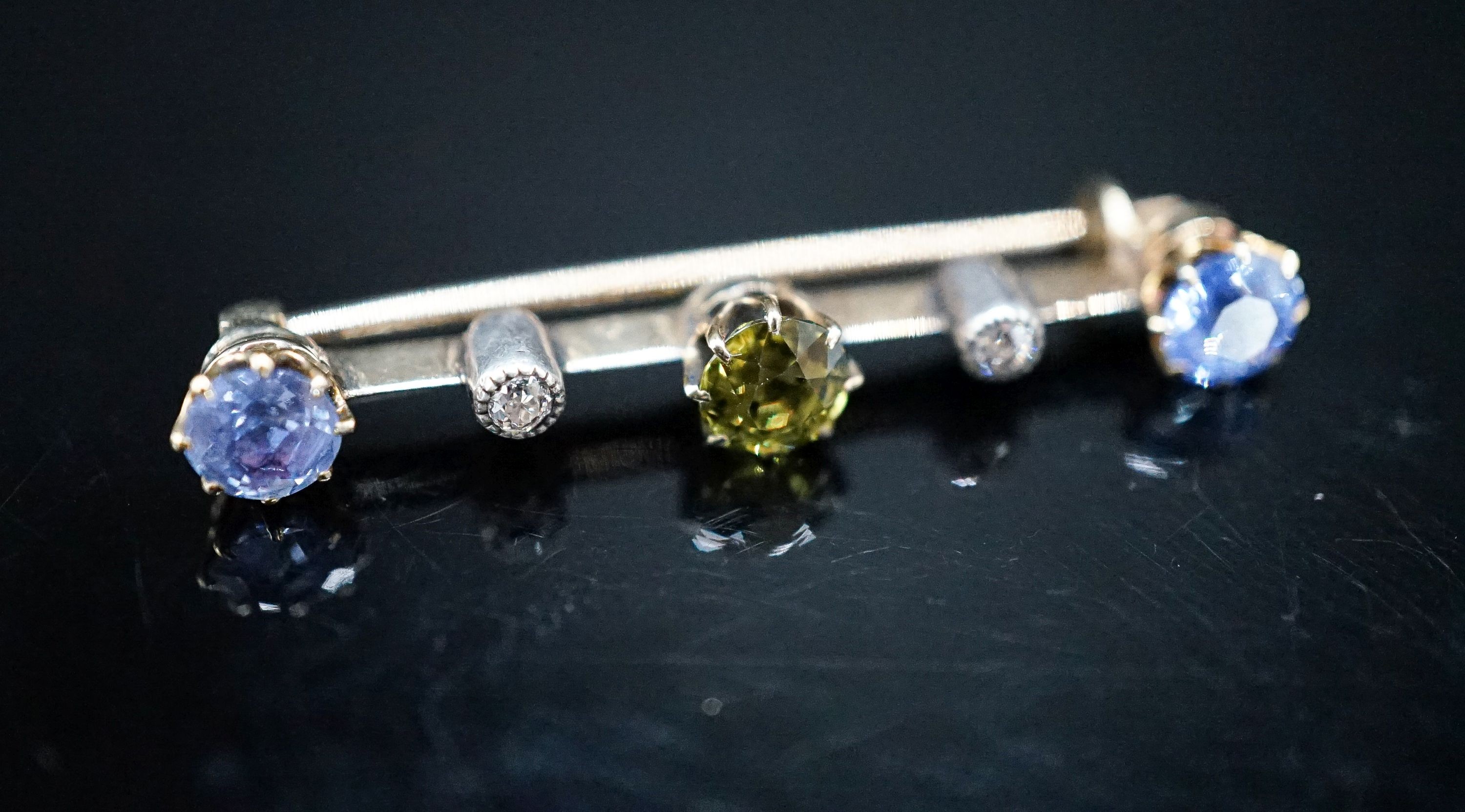 A yellow metal, single stone garnet?, two stone Ceylon sapphire and two stone diamond chip set bar brooch, 37mm, gross weight 2.8 grams.